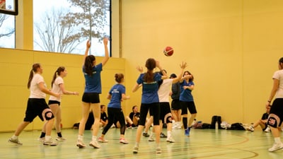 Frauen spielen Basketball in der Turnhalle.