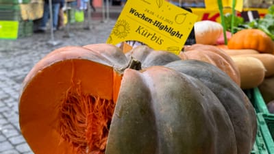 Aufgeschnittener Kürbis auf dem Markt vor historischem Gebäude.