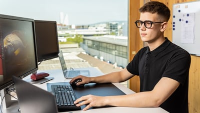 Mann arbeitet an Computer in modernem Büro mit Stadtblick.