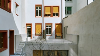 Innenhof mit modernen und klassischen Gebäuden, Balkon und Pflanze.