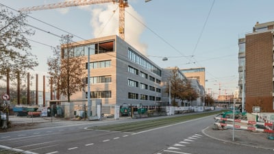 Gebäude im Bau mit Baukran an städtischer Strasse.