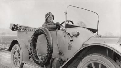 Person in einem alten Auto auf einer Landstrasse.