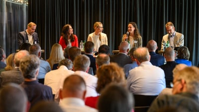 Podiumsdiskussion mit fünf Personen auf einer Bühne vor Publikum.