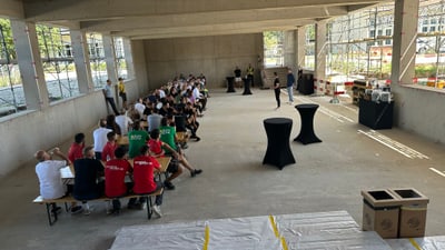Menschen sitzen in einem halbfertigen Gebäude bei einer Veranstaltung.