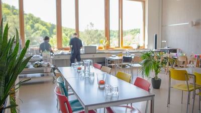 Helle, moderne Kantine mit grossen Fenstern und bunter Bestuhlung.