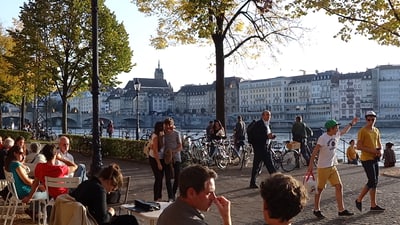 Das Bild zeigt junge und alte Menschen flanierend und sitzend an bei schönem Wetter am Rhein.