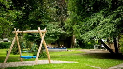 Schaukel auf einem grünen Spielplatz.