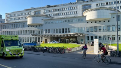 Krankenhausgebäude mit geparkten Fahrrädern und Krankenwagen.