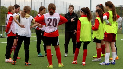 Mädchenfussballtrainer spricht mit Team auf dem Spielfeld.