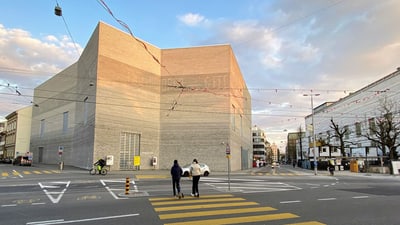 Strassenszene mit zwei Fussgängern und modernem Gebäude im Hintergrund.