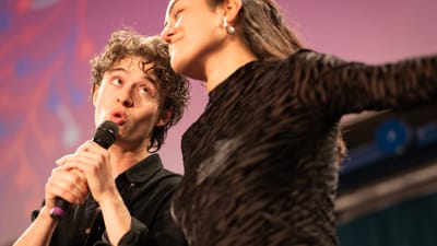 Zwei Personen singen in Mikrofon auf Bühne.