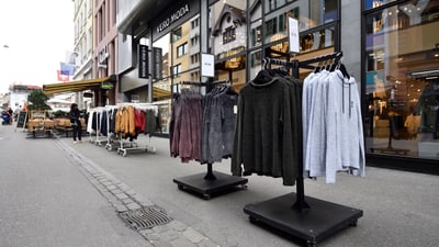 Kleidung auf Verkaufsständern auf einer Einkaufsstrasse.