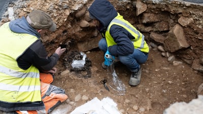 Zwei Archäologen arbeiten an einer Ausgrabungsstelle im Freien.