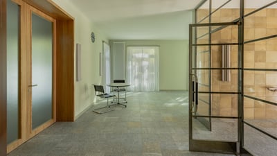 Helle Eingangshalle mit Glastüren und Tisch.