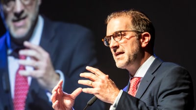 Regierungspräsident hält eine Rede auf einer Bühne, Schappo-Logo sichtbar.