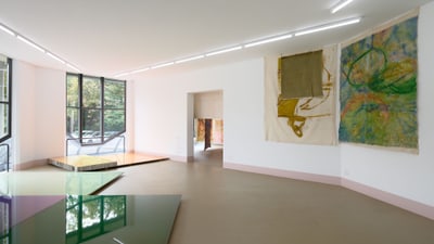 Ein heller Raum mit abstrakter Kunst an den Wänden und grossen Fenstern.