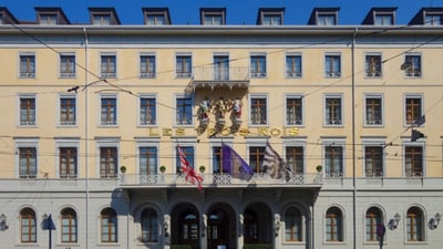 Historisches Gebäude mit Flaggen und Statuen über dem Eingang.