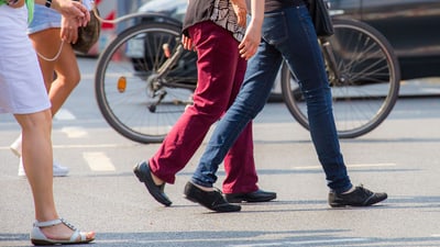 Menschen überqueren die Strasse bei einem Fussgängerüberweg.