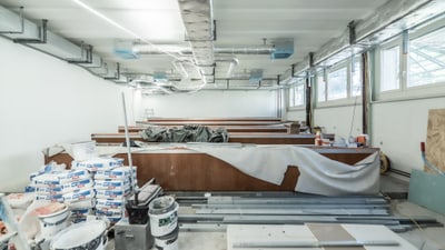 Innenraum einer Baustelle mit Baumaterialien und Lüftungsrohren.