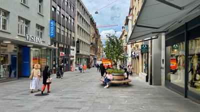 Fussgängerzone in Stadt mit Geschäften und Menschen.