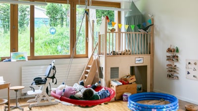 Spielzimmer mit Hochbett, Schwingschaukel und kleinem Planschbecken.