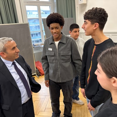 Gruppe junger Menschen unterhält sich dem Departementsvorsteher im Anzug im Raum.