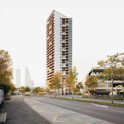 Hochhaus an einer leeren Strasse mit Bäumen bei Tageslicht.