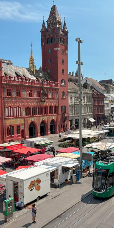 Marktplatz mit bunten Strassenbahnen und historischem Rathausim Hintergrund.