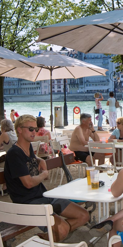 Menschen unter Sonnenschirmen am Rhein