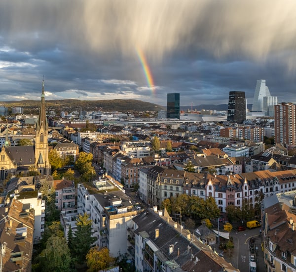 Stadtansicht mit Regenbogen und Kirche.