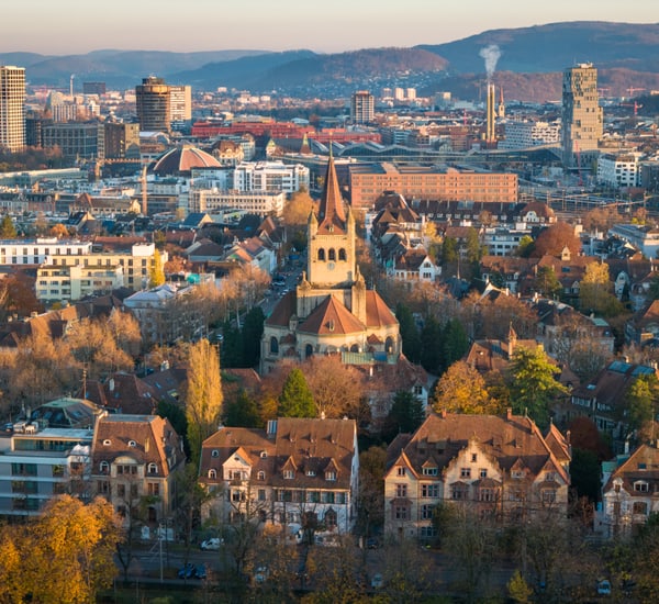 Luftbild einer Stadt mit Kirche und modernen Gebäuden im Hintergrund.