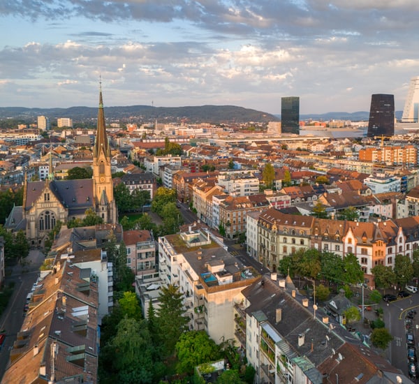 Luftaufnahme einer Stadt mit Kirche und modernen Gebäuden im Hintergrund.