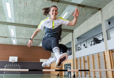Person springt im Fitnessstudio über eine Hürde.