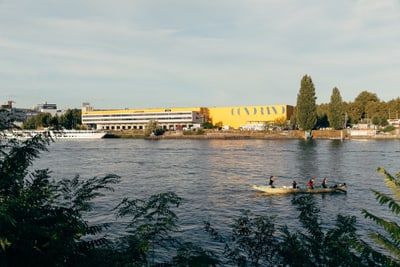 Ruderboot auf dem Fluss vor einer Industrieanlage.