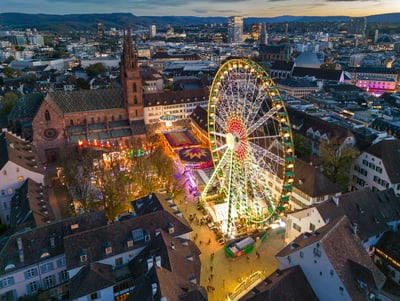 Luftaufnahme des Riesenrads auf dem Basler Münsterplatz bei Abenddämmerung.