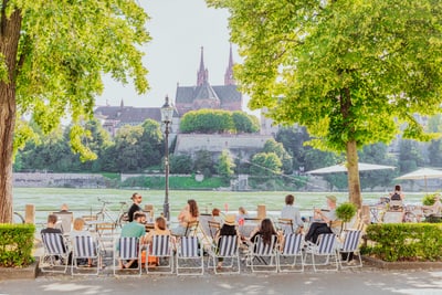 Personen sitzen auf Stühlen mit Blick au den Rhein und das Basler Münster.
