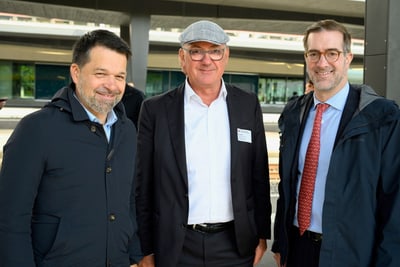 Drei Männer in Anzügen stehen zusammen für ein Foto.",