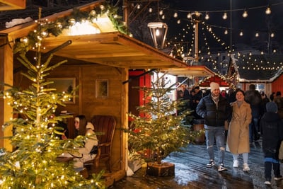 Weihnachtsmarkt mit beleuchteten Bäumen und fröhlichen Besuchern.