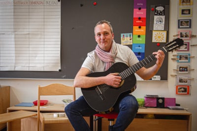 Florin Weber spielt Gitarre in Klassenzimmer vor Tafel.
