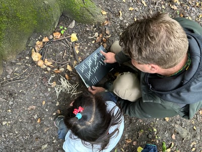 Mann und Kind zählen Sticks im Wald mit Schiefertafel.