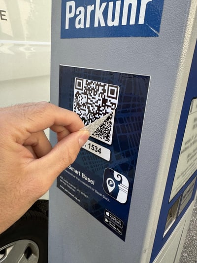 Hand scannt QR-Code an Parkuhr.