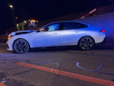 Weisses Auto mit Frontschaden bei Nacht auf Strasse geparkt.