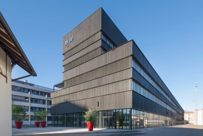 Modernes mehrstöckiges Gebäude aus Glas und Metall unter klarem Himmel.