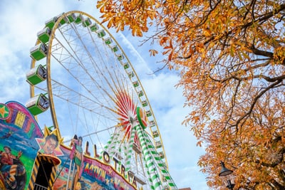 Riesenrad bei Herbstmesse mit bunten Blättern.",