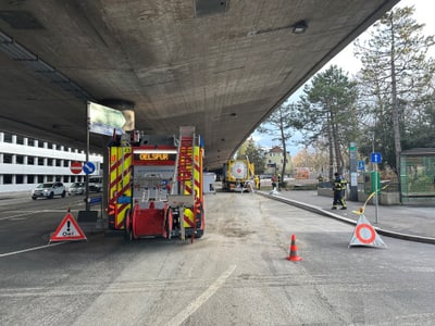 Ölspurbeseitigung unter Brücke mit Einsatzfahrzeugen und Absperrung.",