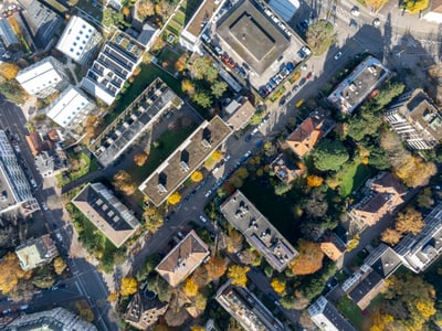 Luftaufnahme von Gebäuden und Strassen mit Bäumen im Herbst.