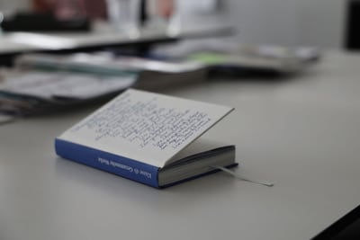 Aufgeschlagenes Buch auf Tisch mit Hintergrund unscharf.