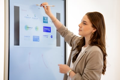 Elena Hatebur zeigt auf Bildschirm mit digitalen Inhalten.