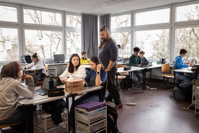 Klassenzimmer mit Schülern und Lehrer Samuel Stirnimann bei der Arbeit an Laptops.