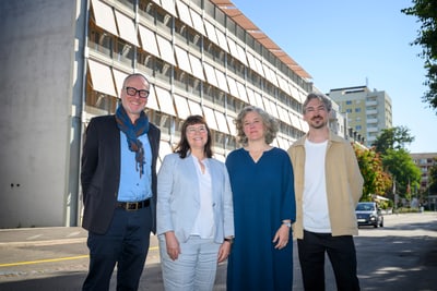 Projektverantwortliche stehen vor dem modernen Gebäude an der Hochbergerstrasse 158 in Basel